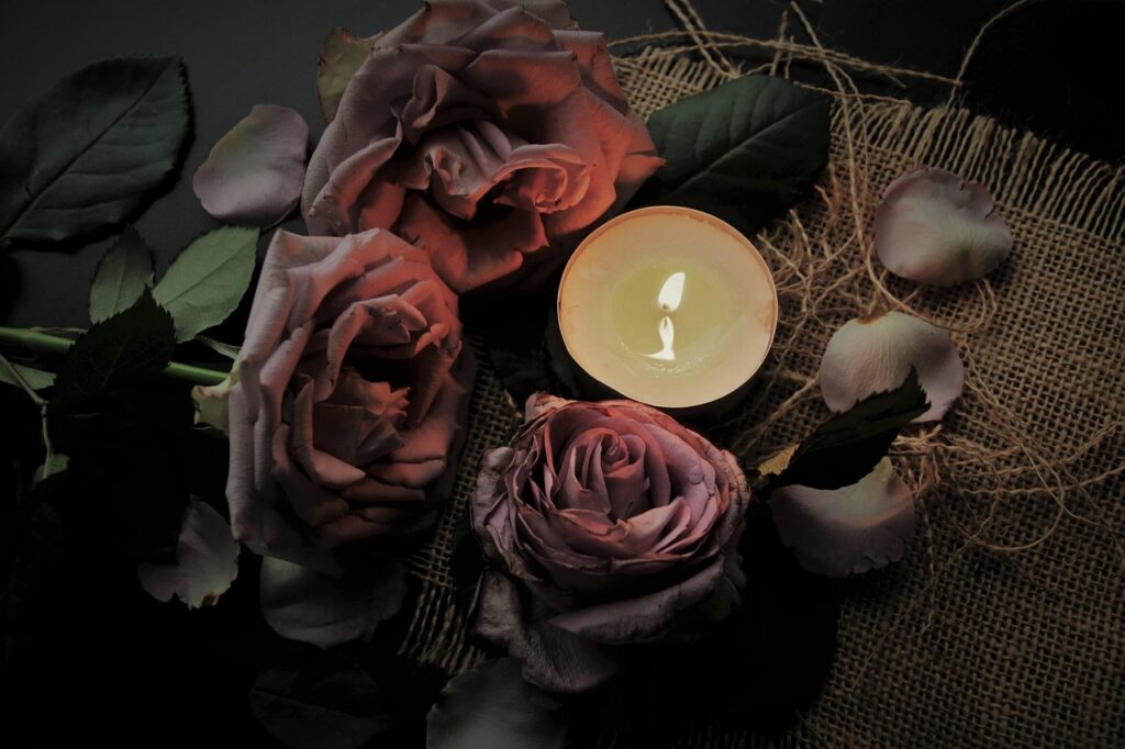 Imagem ilustrativa de velas e flores em homenagem, tema da programação do Cemitério Vertical de Curitiba