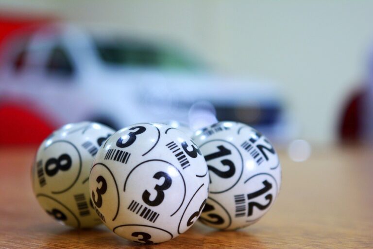 Bolas numeradas de sorteio sobre uma mesa de madeira, com os números 3, 8 e 12 visíveis